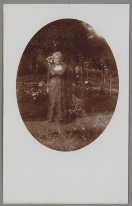Selma Lagerlöf stående i trädgården iklädd mönstrad klänning
